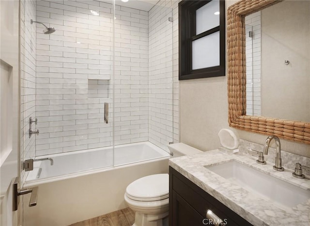 full bathroom with vanity, tiled shower / bath combo, toilet, and hardwood / wood-style flooring