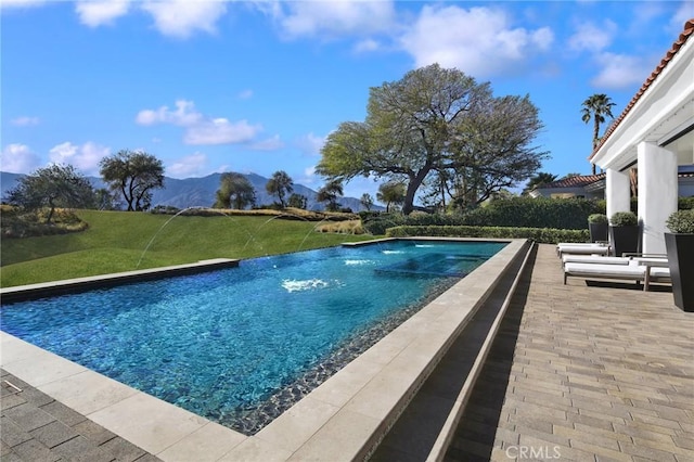 view of swimming pool featuring a mountain view, a lawn, a patio, and pool water feature