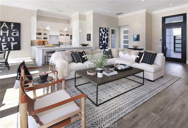 living room with hardwood / wood-style flooring, ornamental molding, and a healthy amount of sunlight