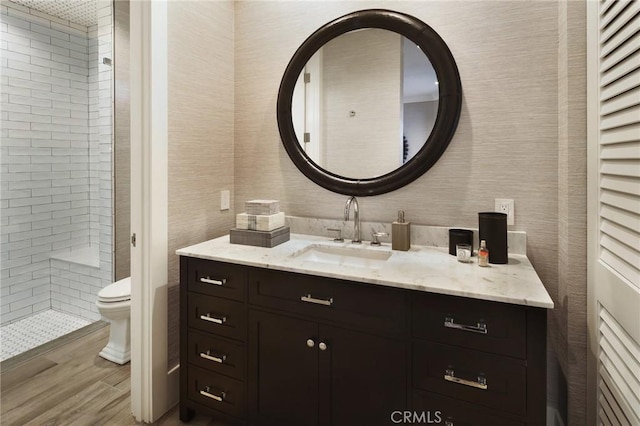 bathroom with vanity, tiled shower, and toilet