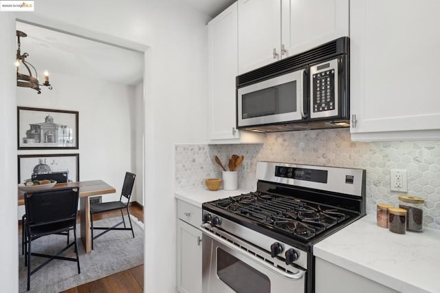 kitchen with gas stove, a notable chandelier, dark hardwood / wood-style floors, white cabinetry, and backsplash