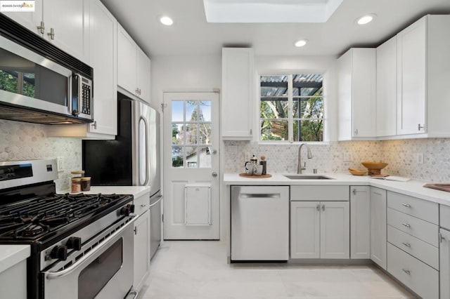 kitchen with sink, stainless steel appliances, white cabinetry, and tasteful backsplash