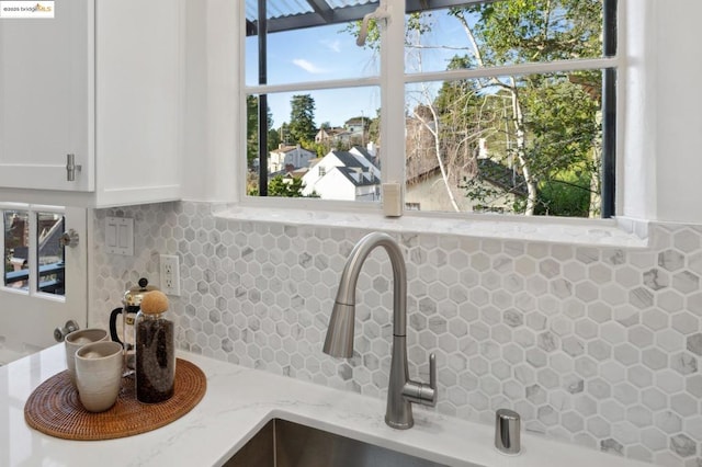 room details featuring light stone countertops, white cabinetry, sink, and decorative backsplash