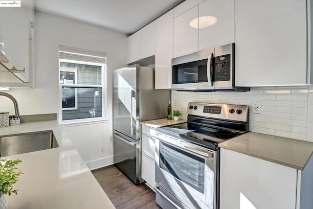 kitchen with sink, white cabinets, dark wood-type flooring, and appliances with stainless steel finishes