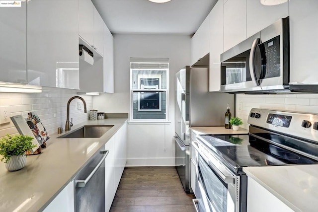 kitchen with white cabinets, appliances with stainless steel finishes, dark hardwood / wood-style flooring, and sink