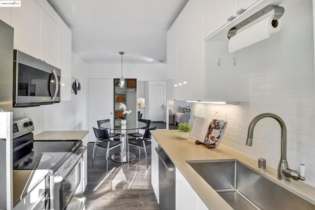 kitchen featuring decorative light fixtures, stainless steel appliances, backsplash, white cabinets, and sink