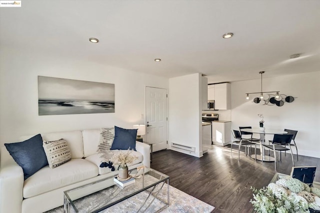 living room with a notable chandelier, baseboard heating, and dark wood-type flooring