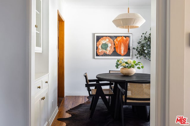 dining area with dark hardwood / wood-style flooring and crown molding