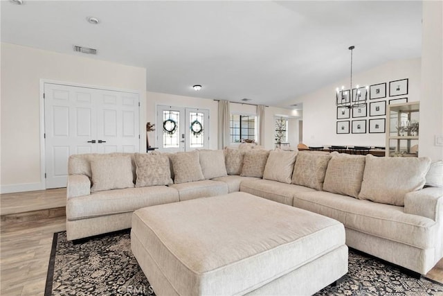 living room with light hardwood / wood-style floors, an inviting chandelier, and lofted ceiling