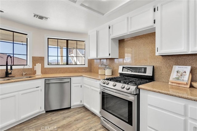 kitchen featuring white cabinets, light wood-type flooring, appliances with stainless steel finishes, and sink