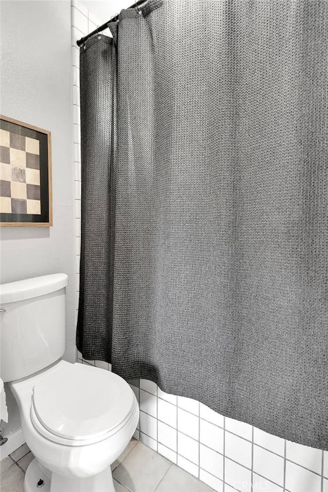 bathroom featuring a shower with shower curtain, tile patterned flooring, and toilet