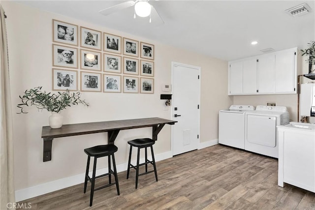 washroom featuring washing machine and dryer, cabinets, ceiling fan, and hardwood / wood-style floors