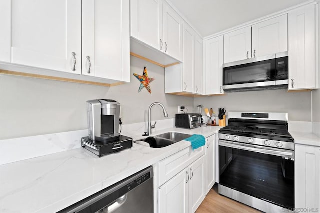 kitchen featuring light stone counters, light hardwood / wood-style flooring, white cabinets, appliances with stainless steel finishes, and sink