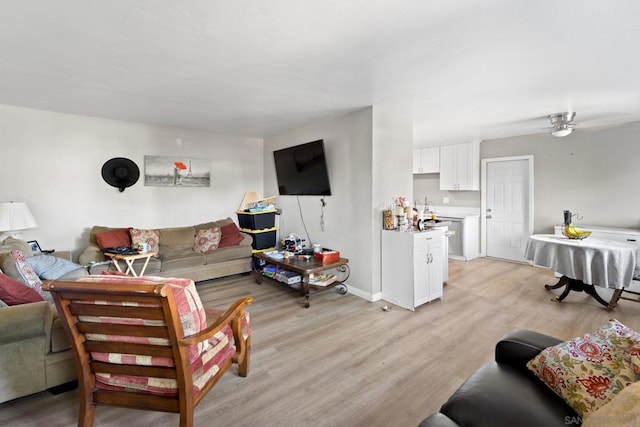 living room featuring sink, light wood-type flooring, and ceiling fan