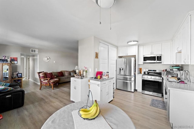 kitchen featuring stainless steel appliances, white cabinets, sink, and light hardwood / wood-style floors