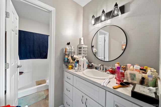 bathroom featuring hardwood / wood-style floors, toilet, walk in shower, and vanity