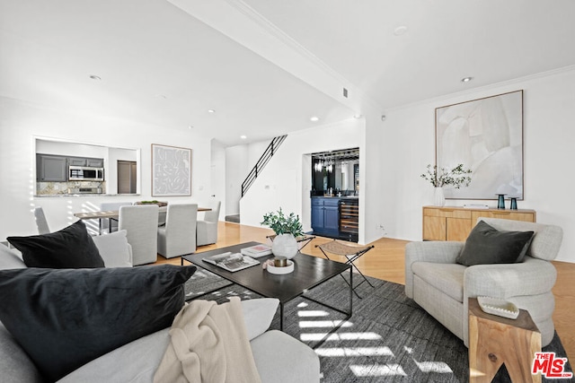 living room with hardwood / wood-style floors, bar area, ornamental molding, and wine cooler