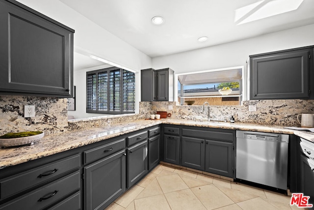 kitchen with light stone countertops, stainless steel dishwasher, light tile patterned floors, tasteful backsplash, and sink