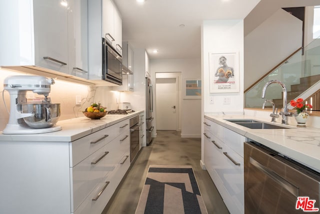 kitchen with stainless steel appliances, sink, white cabinets, tasteful backsplash, and light stone countertops