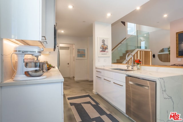 kitchen with dishwasher, light stone countertops, concrete flooring, sink, and white cabinetry