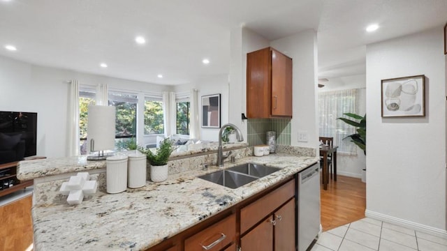 kitchen featuring sink, light tile patterned floors, light stone countertops, and dishwasher