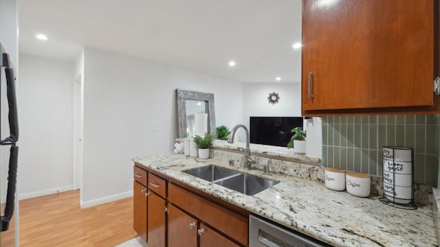 kitchen with sink, light stone countertops, decorative backsplash, stainless steel dishwasher, and light wood-type flooring