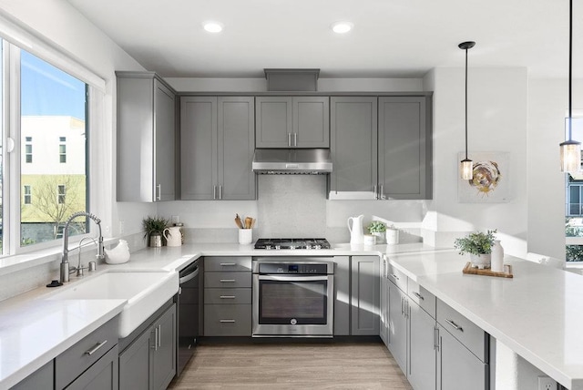 kitchen featuring gray cabinets, pendant lighting, and appliances with stainless steel finishes