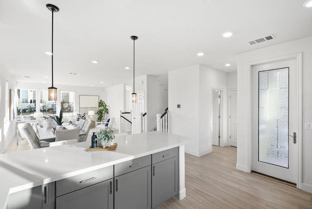 kitchen with decorative light fixtures, light wood-type flooring, and gray cabinetry