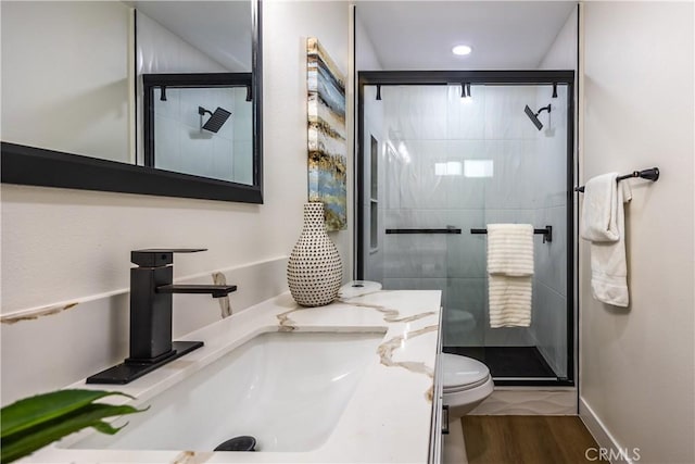 bathroom with walk in shower, hardwood / wood-style floors, vanity, and toilet