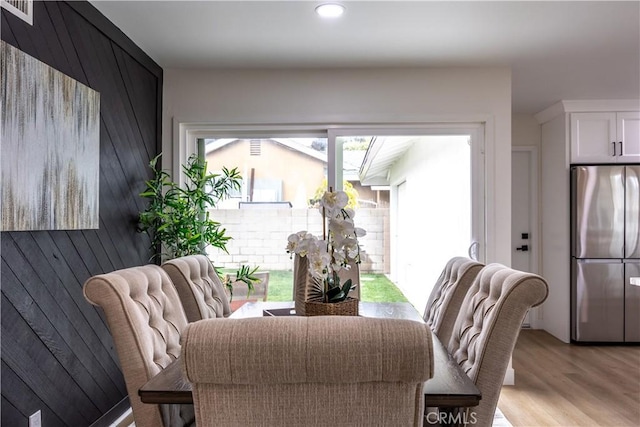 dining space featuring wooden walls and light hardwood / wood-style floors