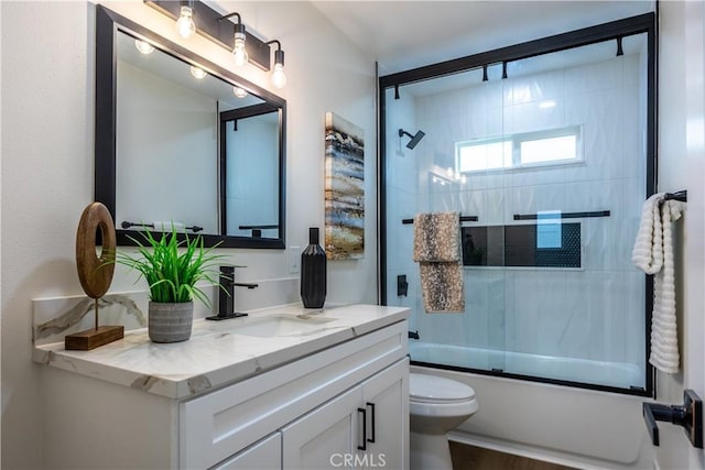 full bathroom featuring toilet, vanity, and bath / shower combo with glass door