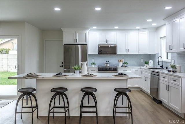 kitchen featuring stainless steel appliances, a kitchen bar, a kitchen island, and white cabinets