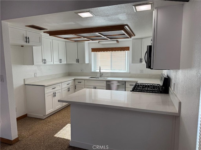 kitchen featuring dishwasher, kitchen peninsula, white cabinets, stove, and sink