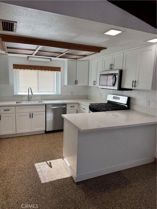 kitchen with sink, white cabinets, a textured ceiling, and appliances with stainless steel finishes