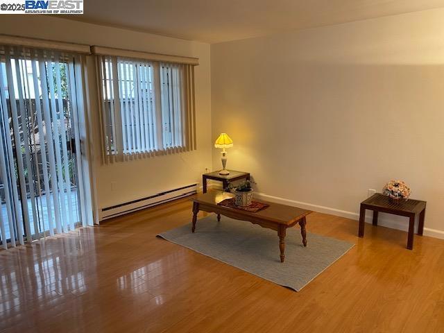 living area featuring baseboard heating and hardwood / wood-style floors