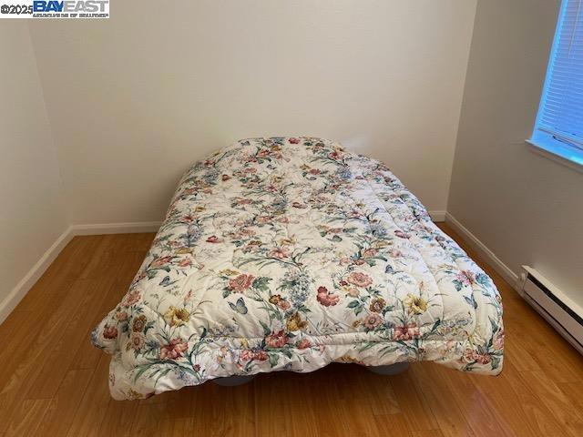 bedroom with hardwood / wood-style flooring and a baseboard heating unit