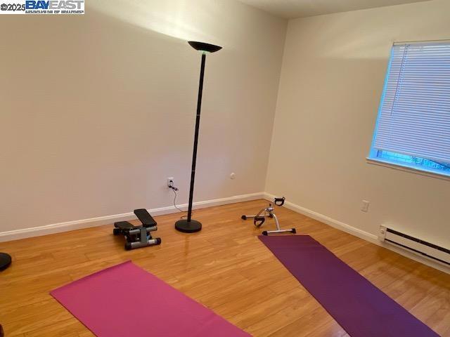 exercise area featuring hardwood / wood-style floors and a baseboard radiator