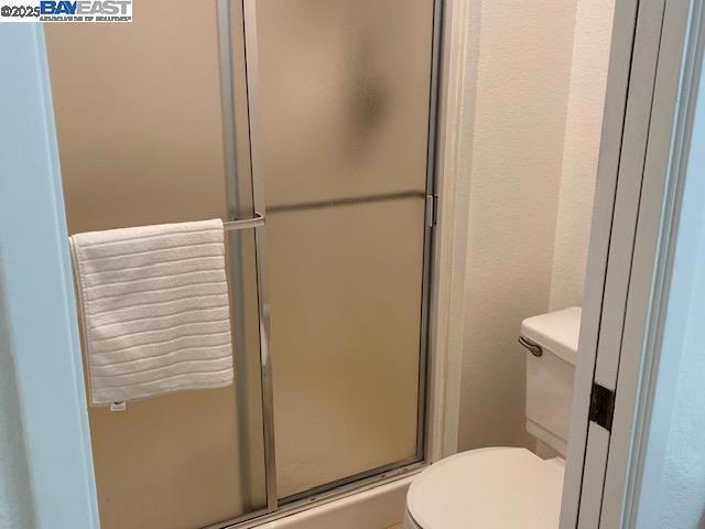 bathroom with toilet and a shower with shower door