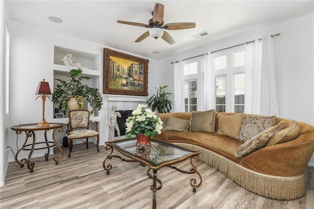 living area with ceiling fan, light wood-type flooring, and built in features