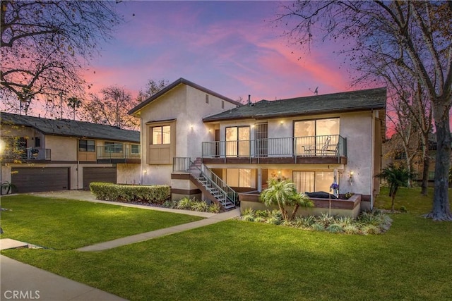 back house at dusk with a yard, a balcony, and a garage