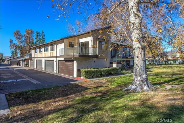 view of front of property with a balcony, a front lawn, and a garage