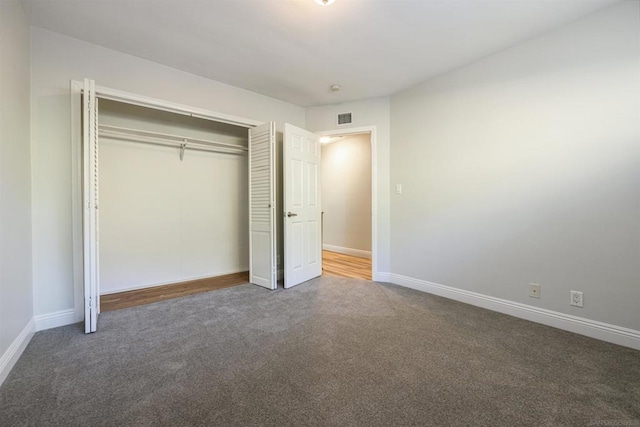 unfurnished bedroom featuring a closet and dark carpet