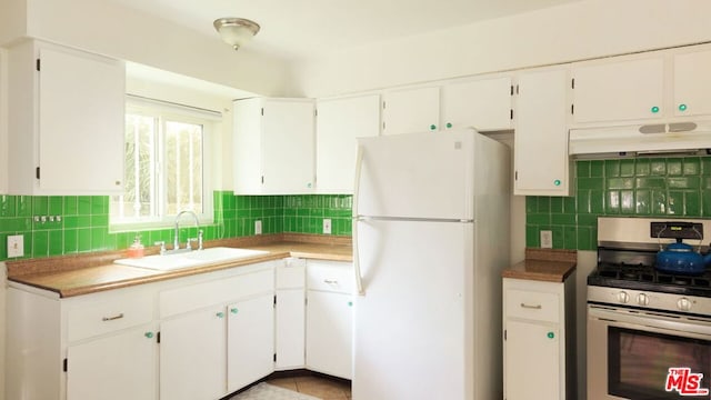 kitchen featuring stainless steel gas stove, white cabinetry, and white fridge