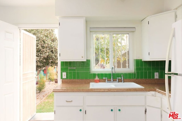 kitchen with sink, white refrigerator, and white cabinetry