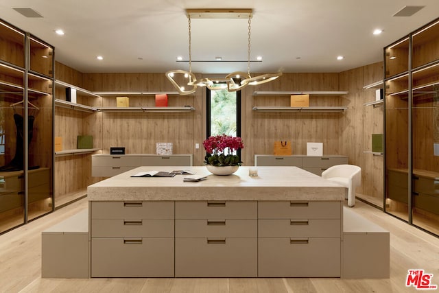 kitchen with decorative light fixtures, white cabinets, wood walls, and a center island