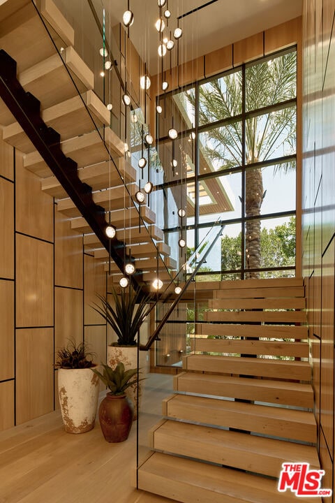 staircase with plenty of natural light, wooden walls, and hardwood / wood-style flooring