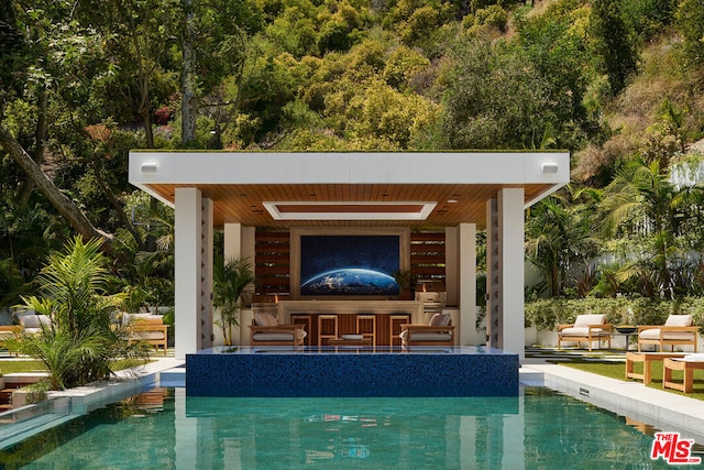 view of swimming pool featuring an outbuilding, a patio, and exterior bar