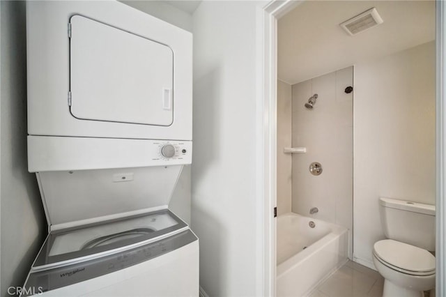 clothes washing area with tile patterned flooring and stacked washer / dryer