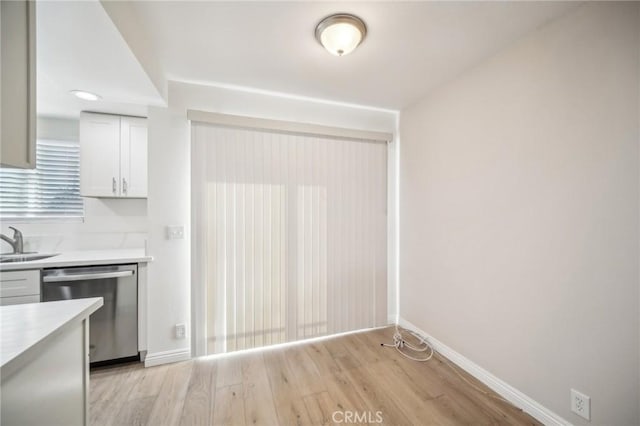 kitchen featuring dishwasher, sink, white cabinetry, and light hardwood / wood-style flooring