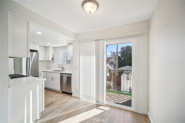 kitchen with sink, white cabinets, stainless steel appliances, and light wood-type flooring